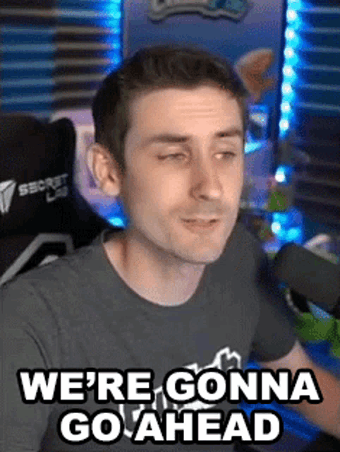 a man is sitting in front of a microphone with the words `` we 're gonna go ahead '' on his face .