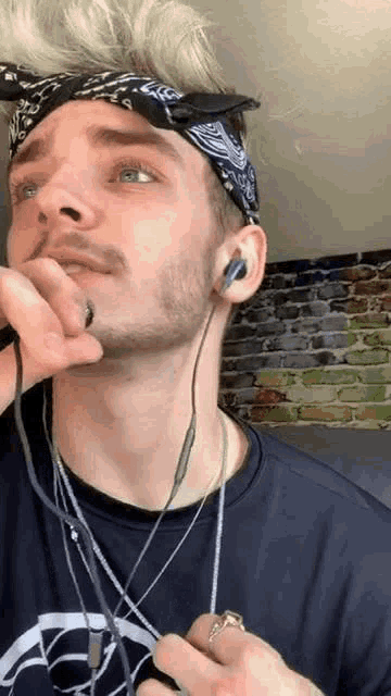 a man wearing a bandana and headphones is holding a microphone .