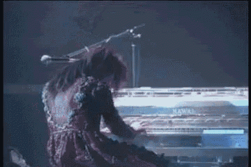 a woman in a red dress is playing a piano with a microphone in the background .