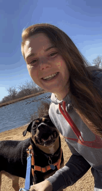 a woman wearing a nike sweatshirt is standing next to a dog