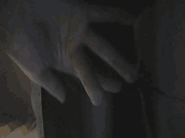 a person is standing in a dark room with a black curtain behind them
