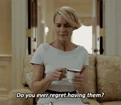 a woman is sitting on a couch holding a cup of coffee and saying do you ever regret having them