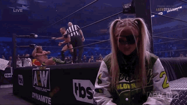 a girl in a wrestling ring wearing a green and white jacket with the number 2 on it