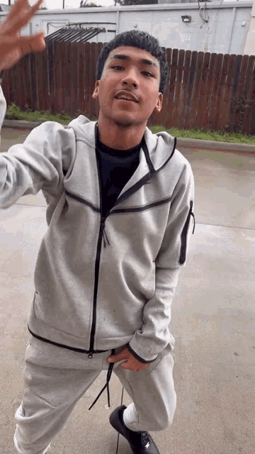 a young man in a grey hoodie and sweatpants is kneeling down