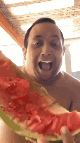 a shirtless man is holding a slice of watermelon