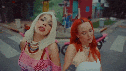 two women with red hair are standing next to each other on a street corner .
