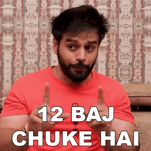 a man in a red shirt says 12 baj chuke hai in front of a wall