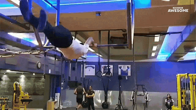 a man is doing a handstand on a bar in a gym with a sign that says awesome