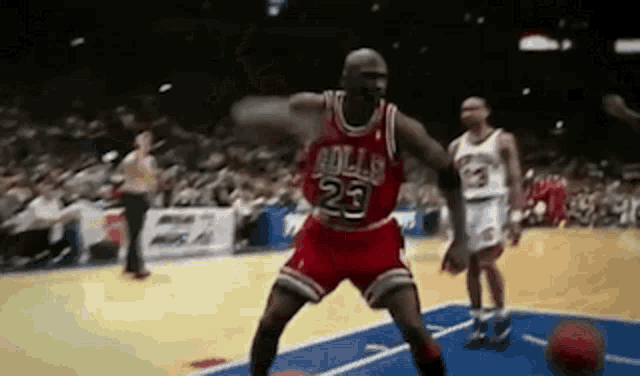 a basketball player in a red jersey with the number 23 on it is dribbling a basketball .