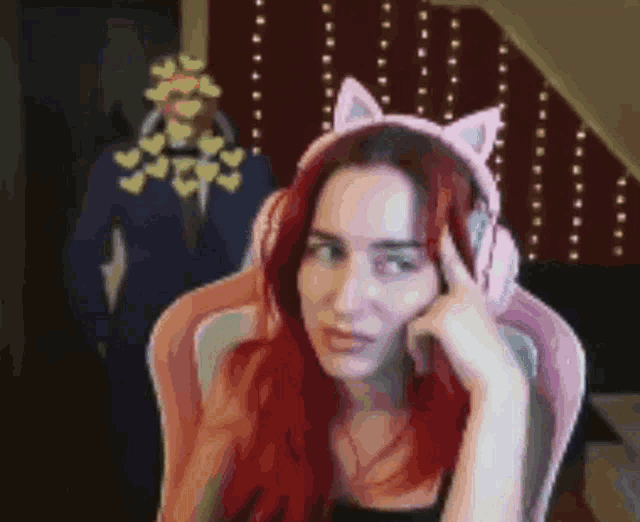 a woman wearing headphones with cat ears is sitting in a chair .