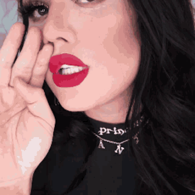 a woman wearing red lipstick and a necklace that says princess on it