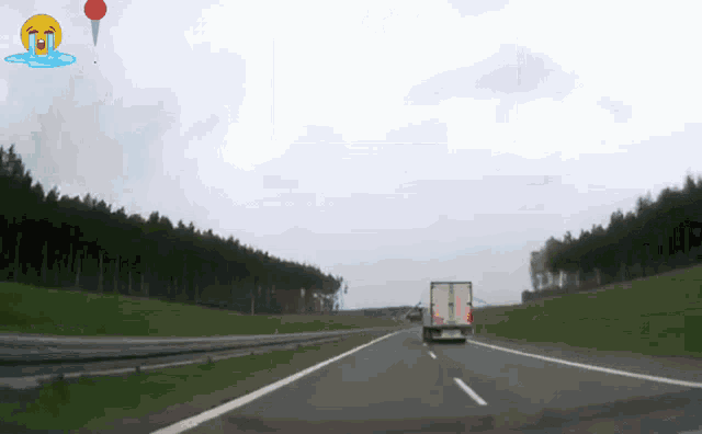 a truck is driving down a highway with a balloon in the sky