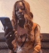 a woman is sitting on a couch looking at a cell phone .