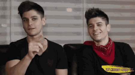 two young men are sitting on a couch and one of them has a bandana around his neck that says los felizdos maya