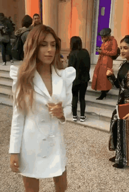 a woman in a white jacket is holding a glass of wine