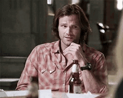 a man is sitting at a table with a bottle of beer on it .