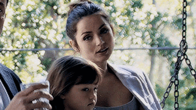 a woman is holding a child in her arms while a man holds a glass of water .
