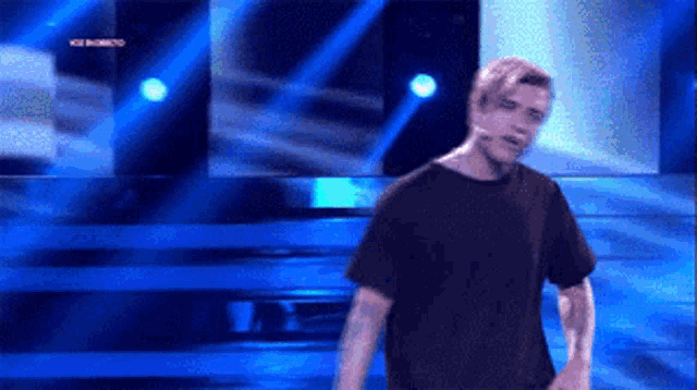 a man in a black shirt is on a stage with a microphone