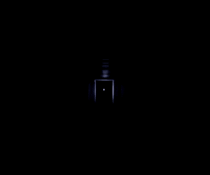 a person is standing in a dark hallway with a light coming from the ceiling .