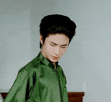 a man in a green shirt with a pattern on it looks down