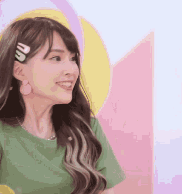 a woman wearing a green shirt and earrings is smiling and looking to the side