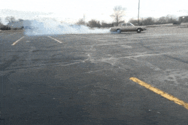 a car is drifting in a parking lot with smoke coming out of the tires
