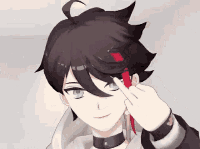 a boy with black hair and blue eyes is holding a red ribbon in his hand .