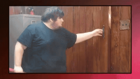 a man in a black shirt is knocking on a wooden door with a sign on it that says l.s.