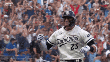 a baseball player wearing a twin cities 23 jersey is running on the field .