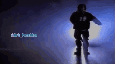 a man is dancing in a dark room in front of a light .