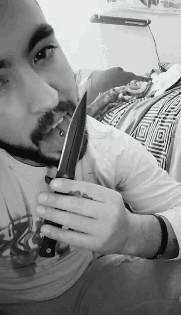a man with a beard is holding a knife in his mouth in a black and white photo
