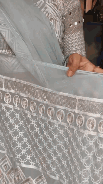 a woman is holding a white cloth with a pattern of circles