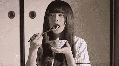 a girl is eating rice with chopsticks from a bowl .