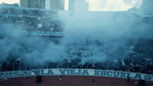 a stadium with smoke coming out of the stands and a banner that says la vieja escuela