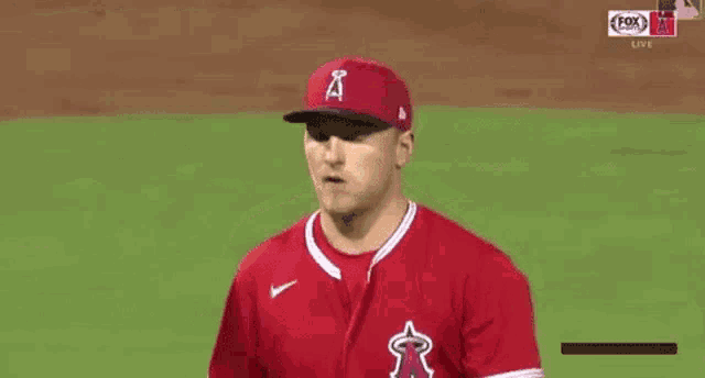a baseball player wearing a red jersey and a hat is standing on a field .