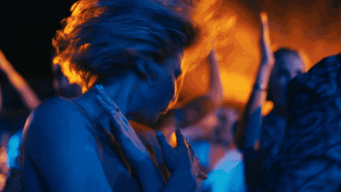 a woman is dancing in a dark room with a fire coming out of her hair