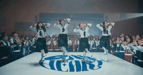 a group of girls are dancing in front of a logo that says ear