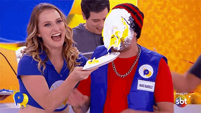 a woman is feeding a man a plate of food with a sbt logo on it