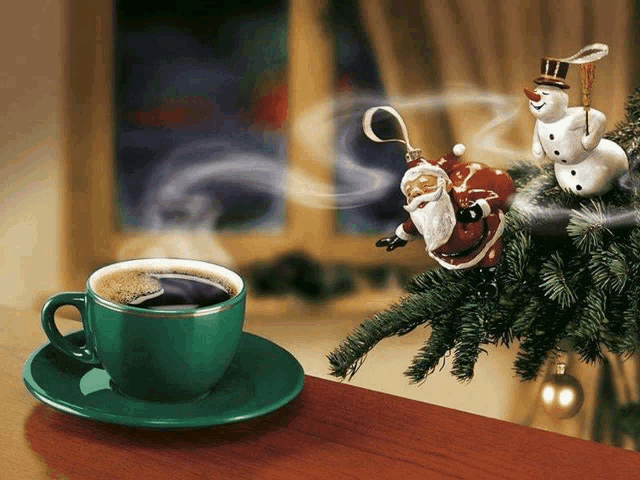 a cup of coffee next to a christmas tree with santa and snowmen