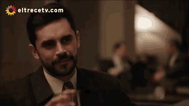 a man in a suit drinking from a glass with eltrecetv.com written on the bottom
