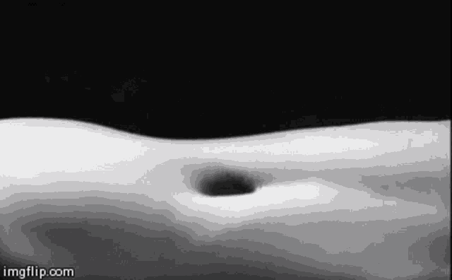 it is a black and white photo of a person 's stomach with a hole in it .