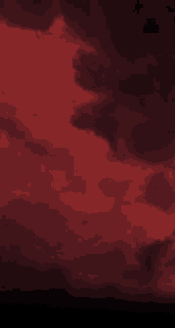 a red sky with dark clouds floating in it