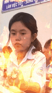 a girl stands in front of a sign that says lam viet tot song
