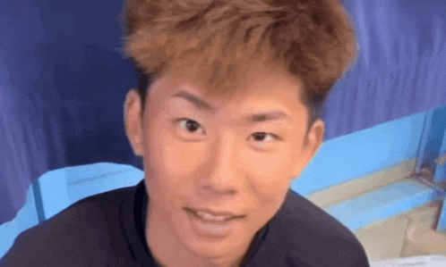 a close up of a man 's face with a blue curtain in the background