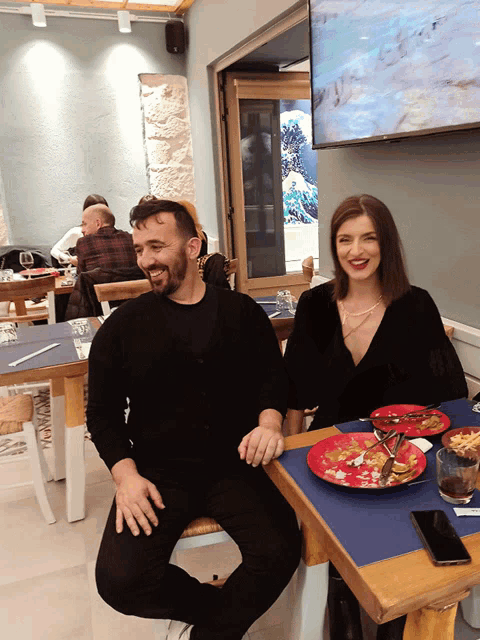 a man and a woman sit at a table in a restaurant