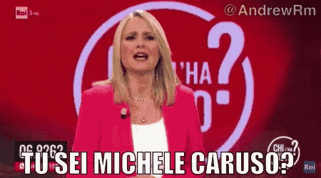 a woman in a pink jacket stands in front of a sign that says ' tu sei michele caruso '