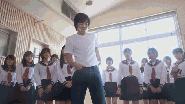 a group of girls are standing around a man in a white shirt