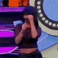 a woman is holding a microphone in front of a purple and blue background .