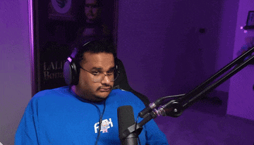 a man wearing headphones and a blue shirt stands in front of a microphone in front of a poster that says lali bond