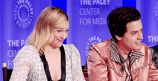 a man and a woman are sitting next to each other at a table and smiling .